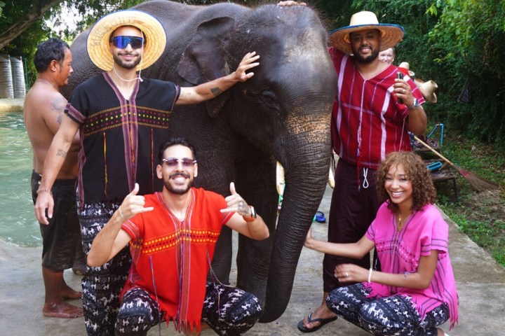 Group of people in colorful attire posing with an elephant at a park.