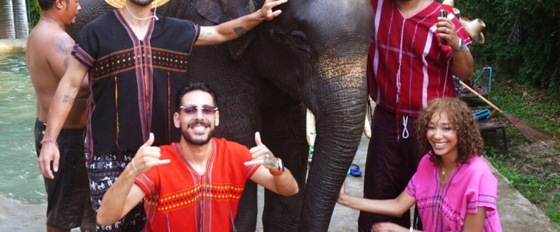 Group of people in colorful attire posing with an elephant at a park.