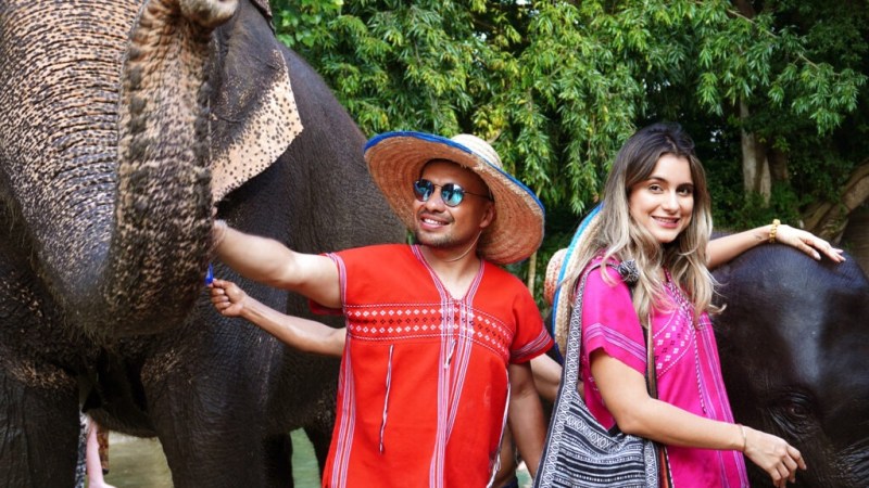 Two people in colorful clothing with elephants at Bangkok Elephant Park.